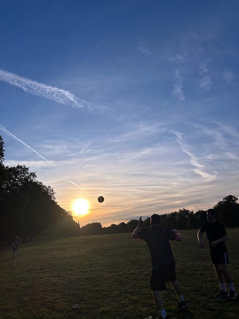 The team out playing a game of football in Hyde park, the sun setting