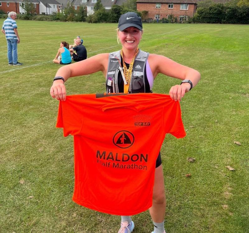 Amy Harris holding a t shirt after completing a half marathon