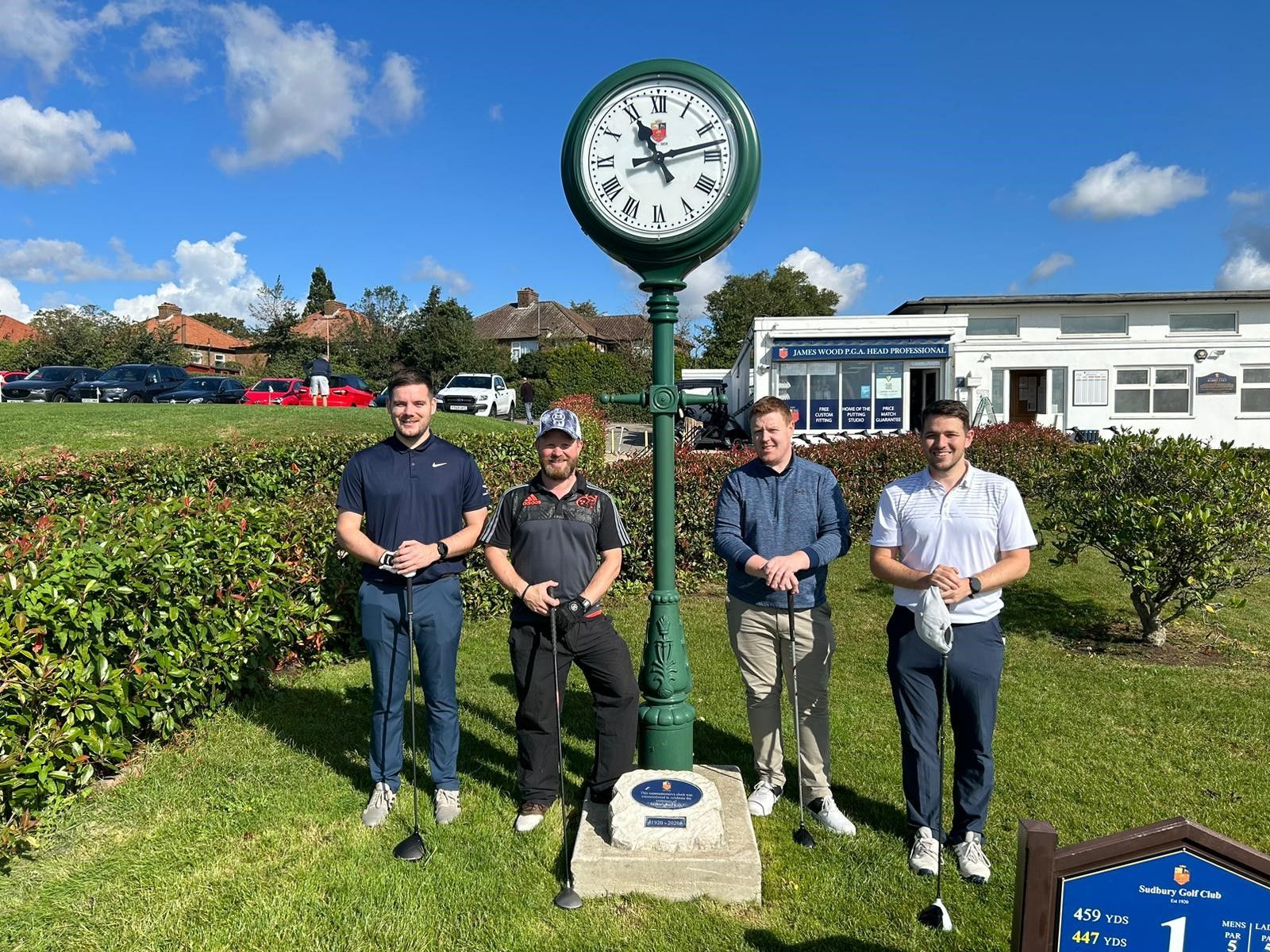 4 men standing for a photo under a large clock