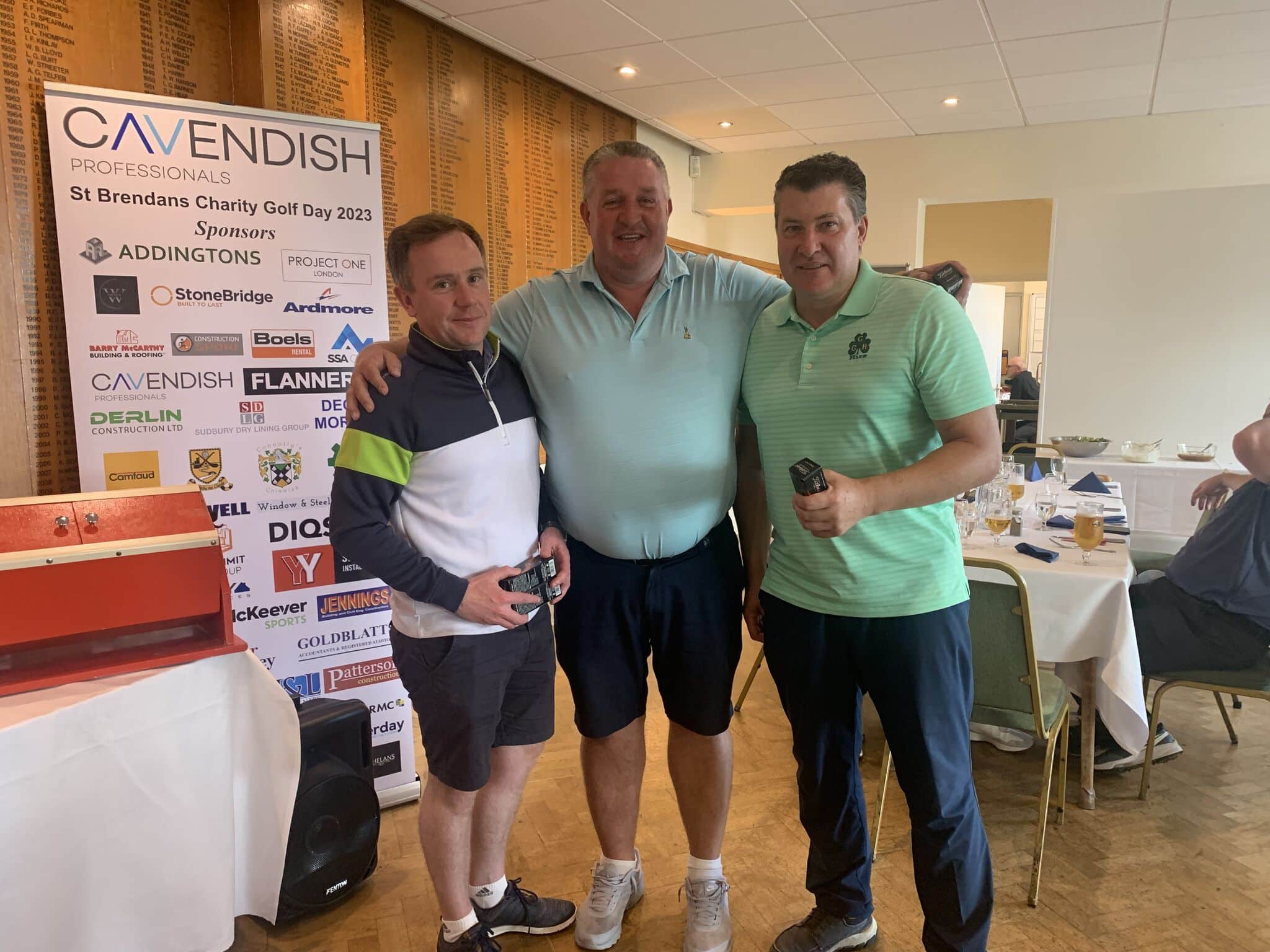 Three men standing for a photo inside a golf club